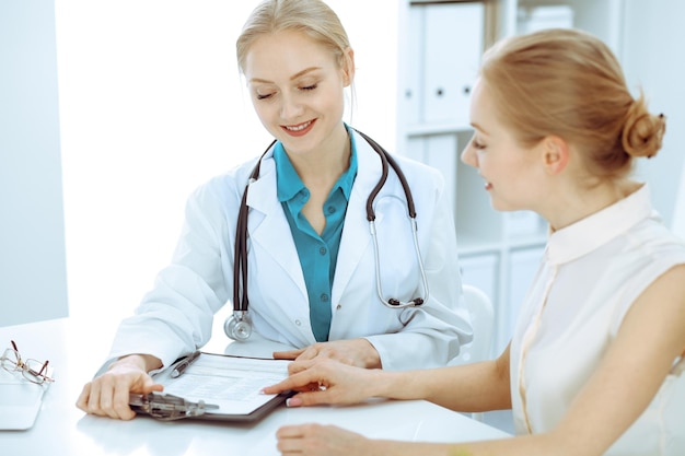 Doctor and patient sitting at the desk. The physician or therapist makes a diagnosis. Health care, medicine and patient service concept.