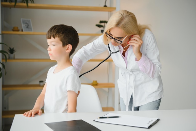 Doctor pediatrician examines child Female doctor puts a stethoscope to a child's chest and listens to the little boy's heartbeat and lungs Concept of health care and pediatric medical examination