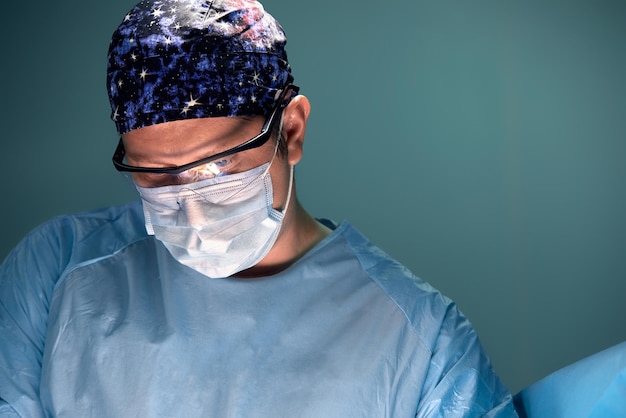 Doctor performing surgery in dark operation room with lamp on background