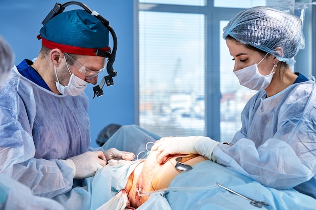 The doctor performs an operation to reconstruct the female breast. Close-up of plastic surgeon performing implantation procedure, breast cancer