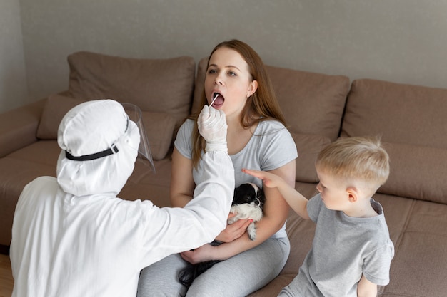 Doctor in personal protective equipment doing nasopharyngeal swab to patient with covid-19 infection