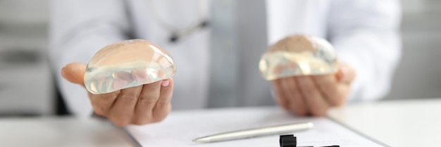 Doctor plastic surgeon holds silicone breast implants breast augmentation and lift concept