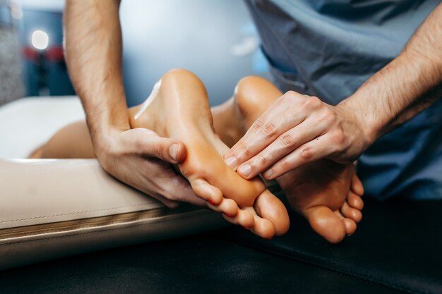 Photo the doctor-podiatrist does an examination and massage of the patient's foot in the clinic.