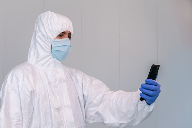 Doctor in PPE consulting mobile application on smartphone during an pandemic of covid 19 in a hospital of Spain.