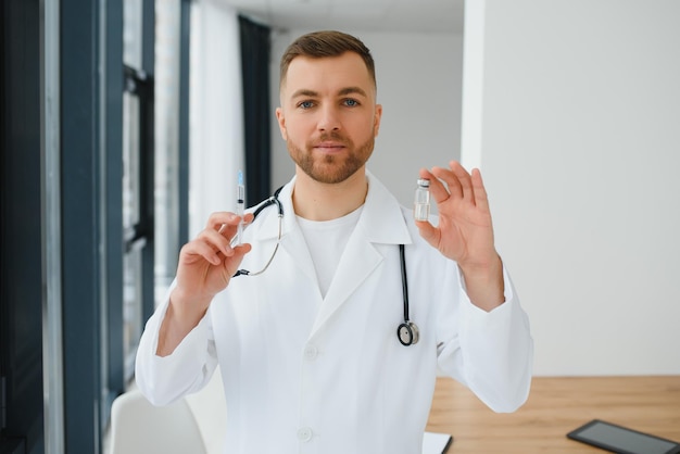 Doctor in PPE holding a vial or bottle vaccine against coronavirus Covid 19 new Omicron variant or strain in his hand close up Concept of vaccination trial and treatment due to SARSCoV2 pandemic