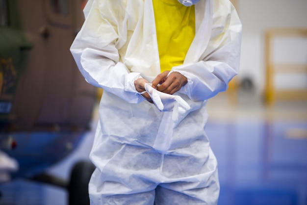 Doctor in PPE uniform putting medical gloves on