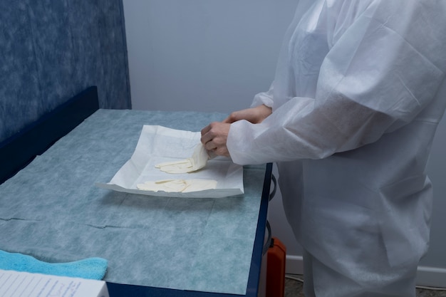 A doctor prepares to attend to a patient.
The woman prepares (protective suits,googles,gloves and masks) all the necessary protections to protect itself from covid-19