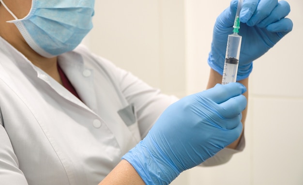 Doctor prepares a syringe with an injection, close-up