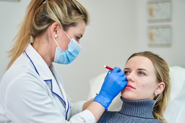 Doctor preparing female patient for cosmetic surgery in clinic