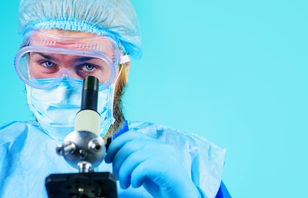 Doctor in protective mask gloves examining sample with microscope research in laboratory closeup