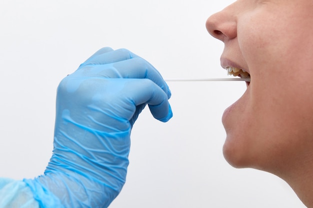 Doctor in a protective suit taking a throat and nasal swab from a patient to test for possible