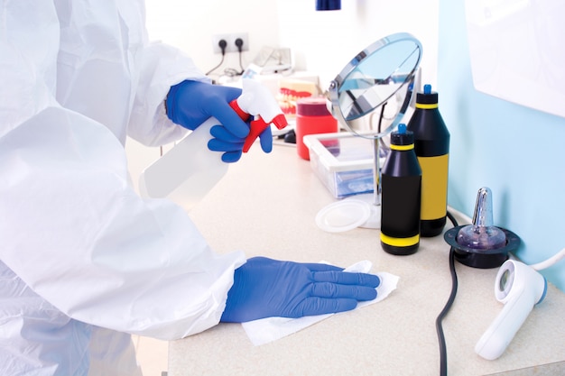 Doctor in protective suit uniform cleans the laboratory.