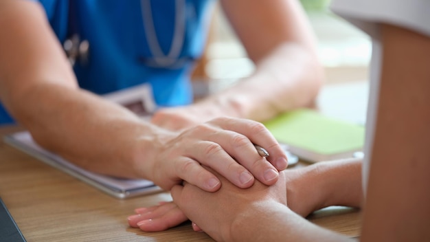 Photo doctor puts his hand on hand of patient explaining dangerous diagnosis medical checkup and