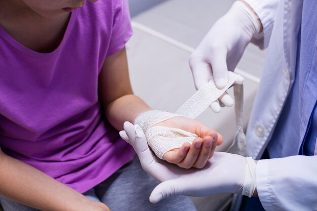 Doctor putting bandage on injured hand of patient