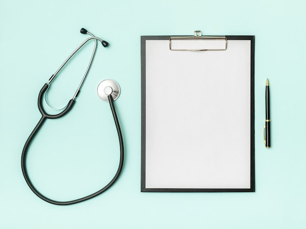 Doctor's desk top view. Stethoscope and notebook on a colored table