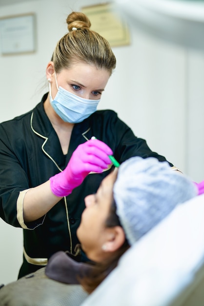 Doctor's hand in glove making marks on patient's face