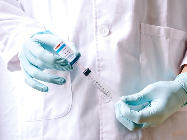 A doctor's hand removing the Coronavirus vaccine from a vial. Covid-19