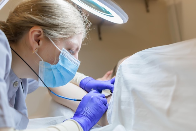 Doctor's work on electrolysis with tweezers and an electrode he removes unwanted hairs