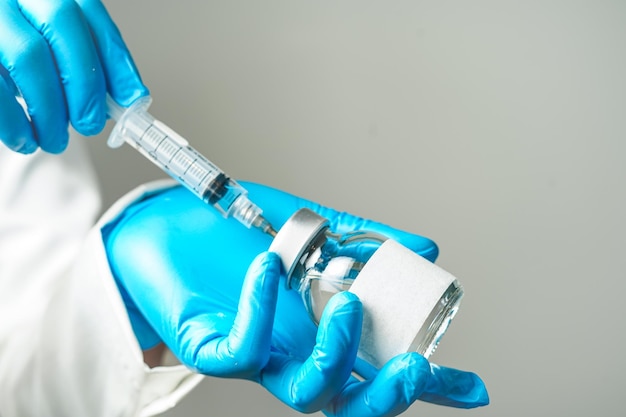 Photo doctor or scientist holding a syringe with ampules vaccine bottle for injection