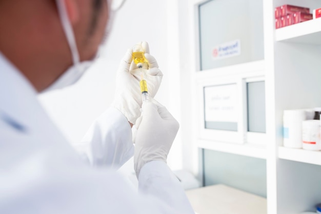 A doctor or scientist in a laboratory holding a syringe containing a liquid vaccine for a child or elderly person Concept disease medical treatment science