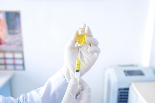 A doctor or scientist in a laboratory holding a syringe containing a liquid vaccine for a child or elderly person Concept disease medical treatment science