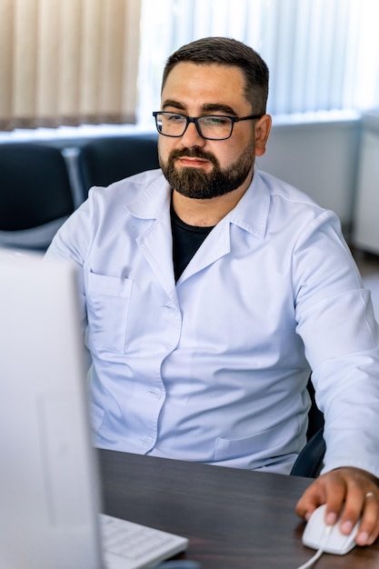 Doctor in scrubs is sitting at desk near computer Sitting in chair in medical office