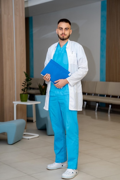 Doctor in scrubs standing at office. Folder in hands. Medical results at doctor`s hands.