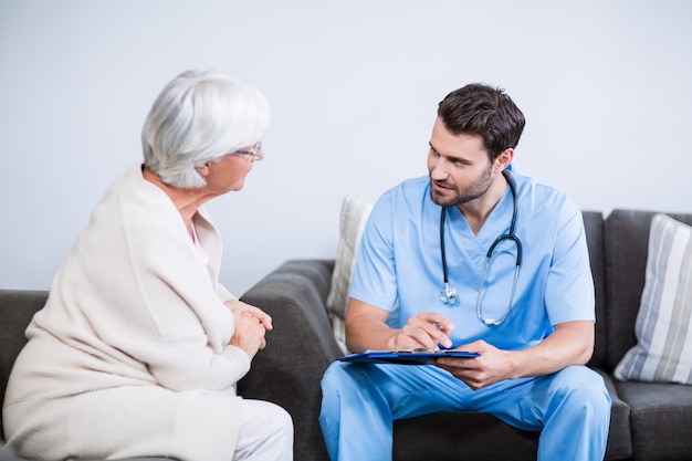 Doctor and senior woman discussing on clipboard