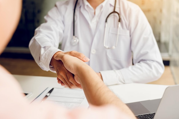 Doctor shaking hands with older patient in the clinic room