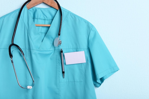 Doctor shirt with stethoscope on hanger on blue background