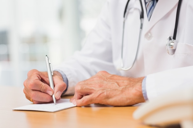 Doctor sitting at his desk writing a prescription