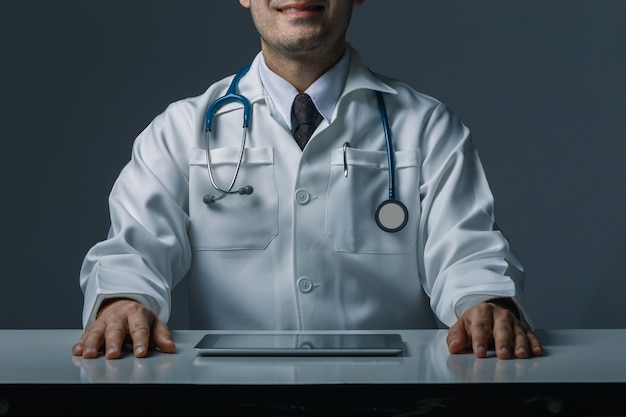 Doctor sitting with tablet on table