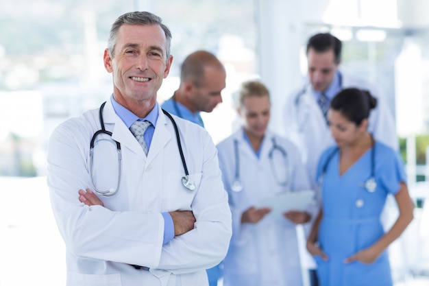 Doctor smiling at camera while his colleague discussing 