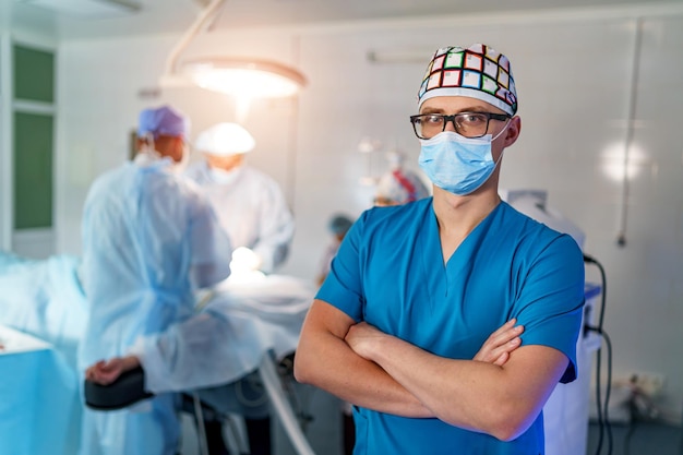 Doctor stands crosshands in medical mask Medical team on background Doctor in glasses with medical mask on face Close up shot