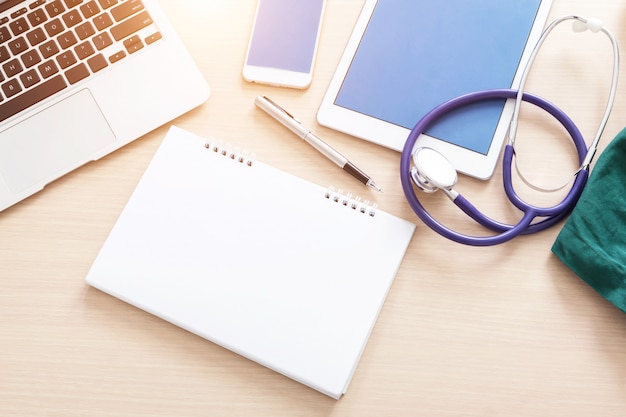 Photo doctor table with medical accessories and blank notebook.