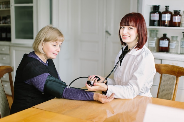 Doctor taking blood pressure of female patient at office