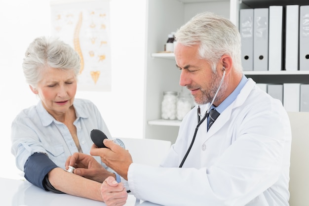 Doctor taking the blood pressure of his retired patient