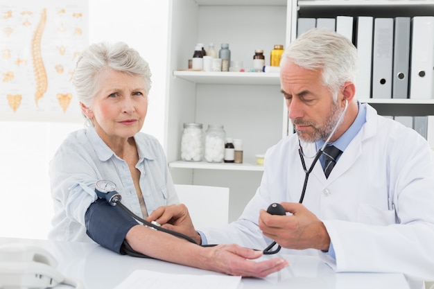 Doctor taking blood pressure of his retired patient