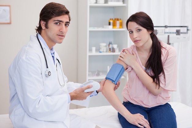 Doctor taking female patients blood pressure