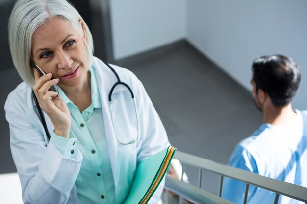 Photo doctor talking on mobile phone while walking on staircase