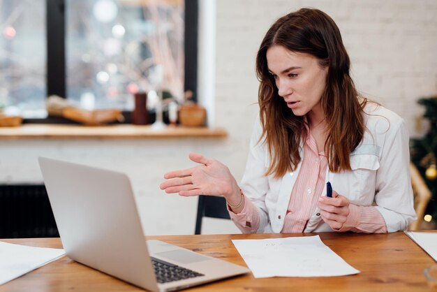 Doctor talks to a patient online in front of her laptop computer