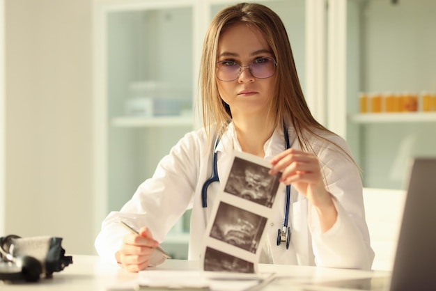 Doctor therapist examining result of ultrasound examination of abdominal cavity in clinic