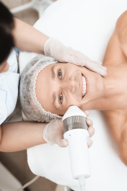 Doctor treats the skin of a man with a modern photoepilator.