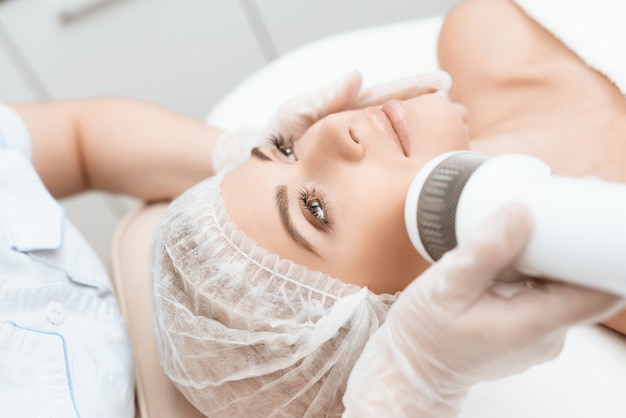 Doctor treats woman's face in salon.