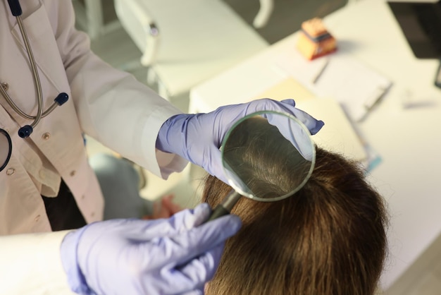 Doctor trichologist examining scalp of patient in clinic closeup diagnosis and treatment of