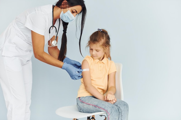 Doctor in uniform making vaccination to the little girl