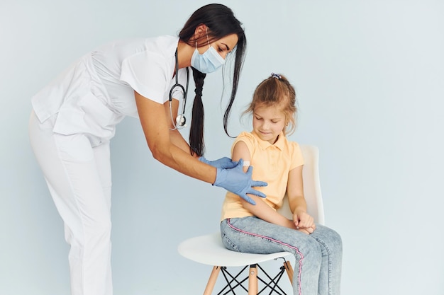 Doctor in uniform making vaccination to the little girl