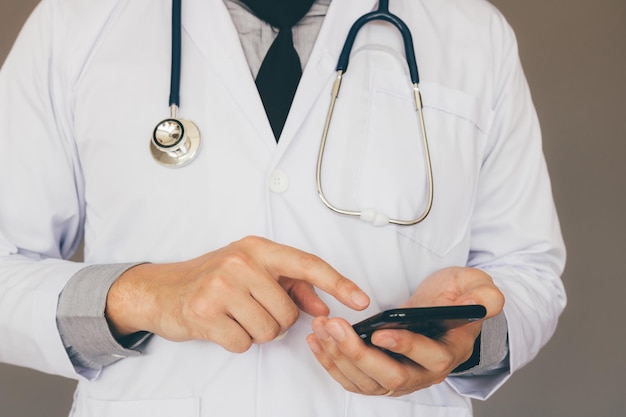 Doctor using smartphone and typing to screen