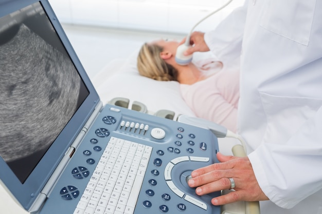 Photo doctor using sonogram on neck of female patient