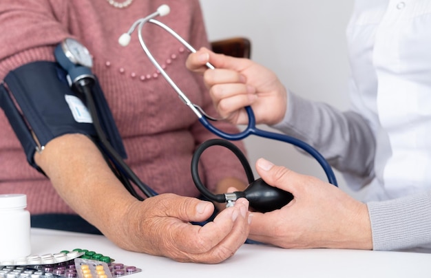 Doctor using sphygmomanometer with stethoscope checking blood pressure to a patient in the hospital